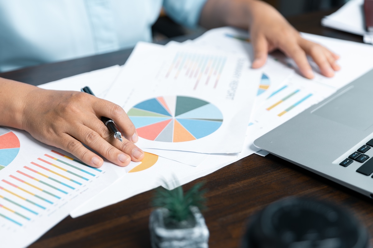 Persons hands holding paper with multi-colored pie chart.